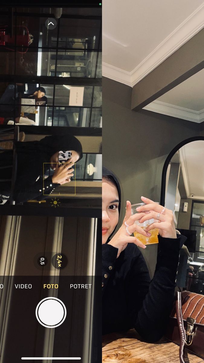 a woman sitting at a table with a glass in front of her and another person taking a selfie