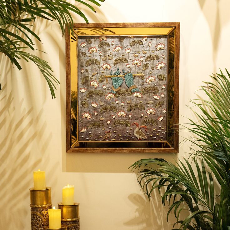 a painting hanging on the side of a wall next to candles and potted plants