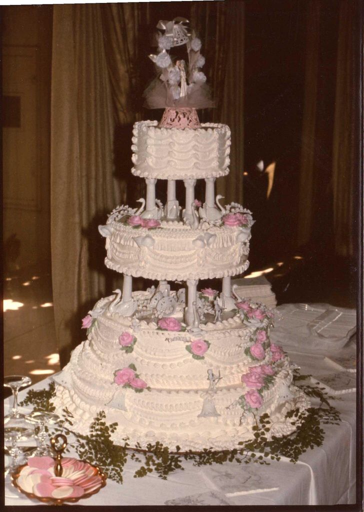 a three tiered wedding cake with teddy bears on top and pink flowers in the middle