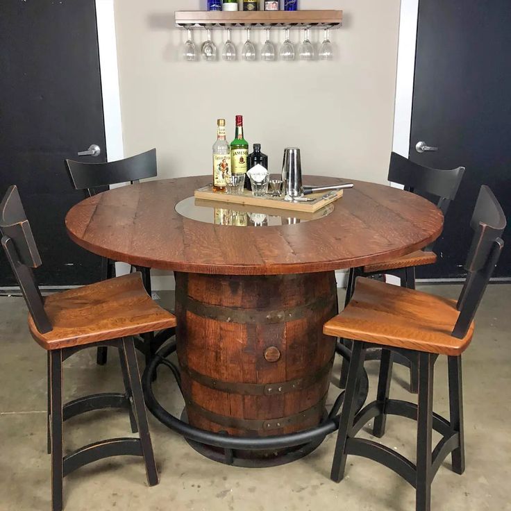 a wooden barrel table with four chairs around it and bottles on the wall behind it