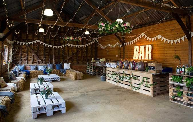 the inside of a barn with hay bales and lights hanging from the rafters