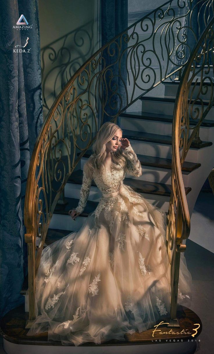 a woman in a white dress is sitting on a stair case and talking on the phone