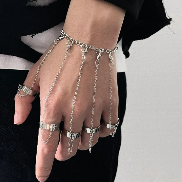 a person wearing silver chains and rings on their hands