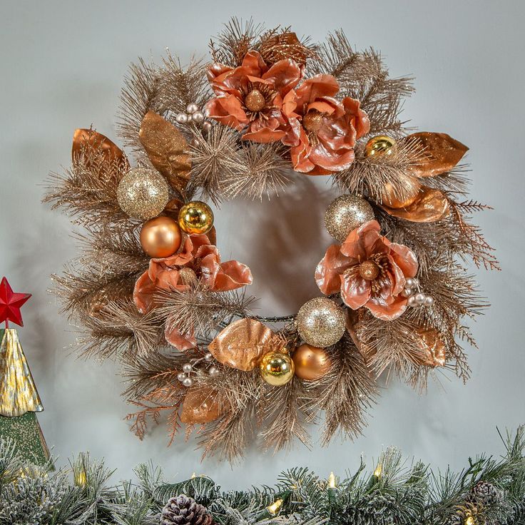 a christmas wreath is hanging on the wall next to a small tree with ornaments around it