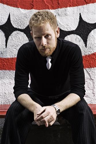 a man sitting on top of a bench in front of a red and white wall