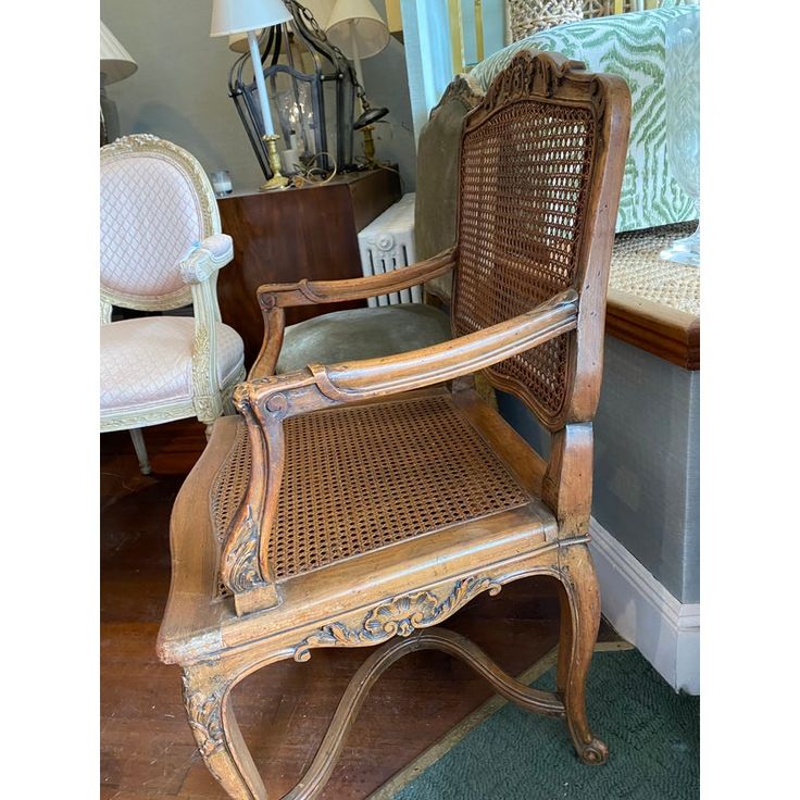 an old wooden chair sitting on top of a hard wood floor next to a lamp