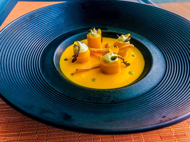 a blue plate topped with food on top of a wooden table next to an orange cloth