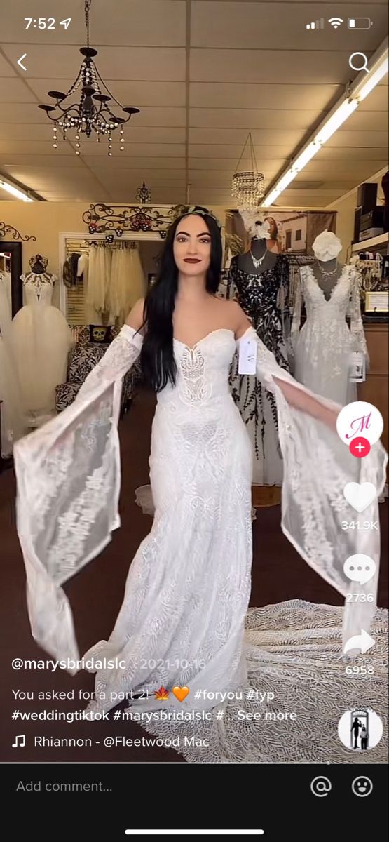 a woman in a white dress standing next to some dresses