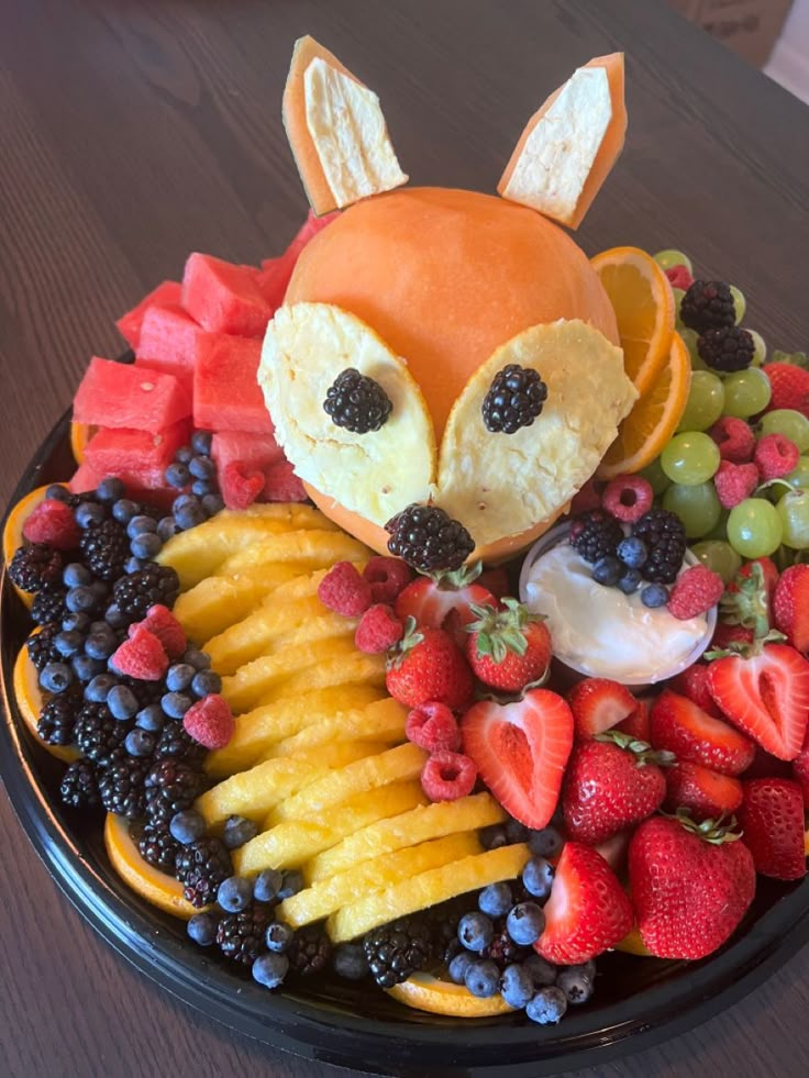 a plate topped with fruit and a stuffed animal face on top of it's head