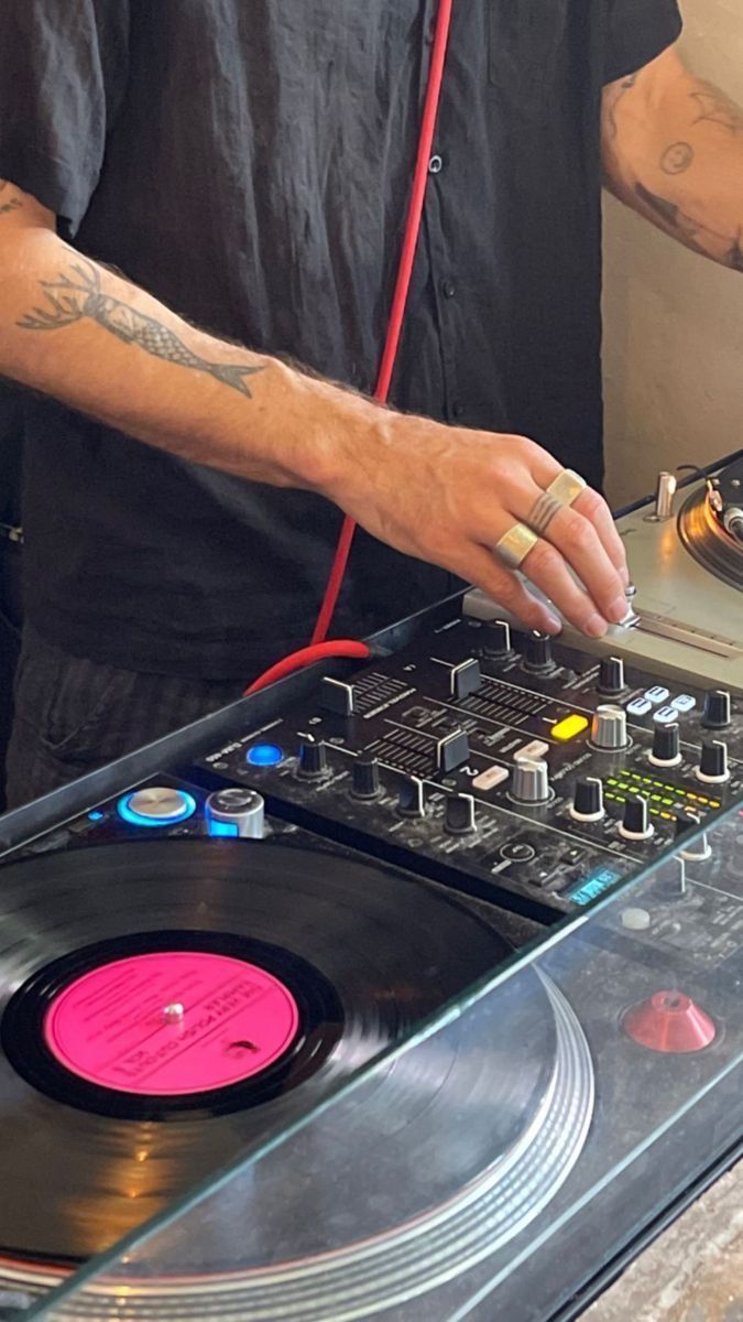 a man that is standing in front of a dj's turntable with his hands on it