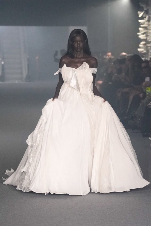 a model walks down the runway in an off - shoulder white gown with ruffles