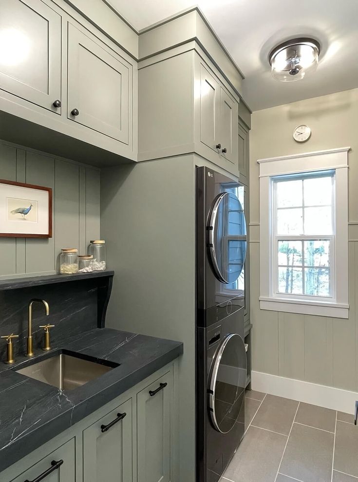 a washer and dryer in a small room with tile flooring on the walls