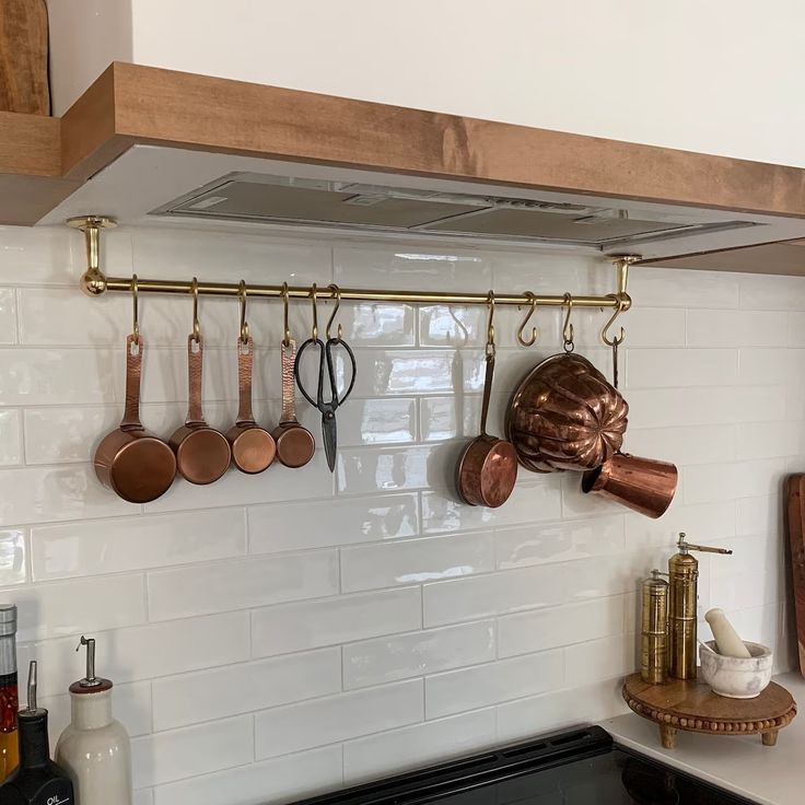 pots and pans are hanging on the wall above the stove top in this kitchen