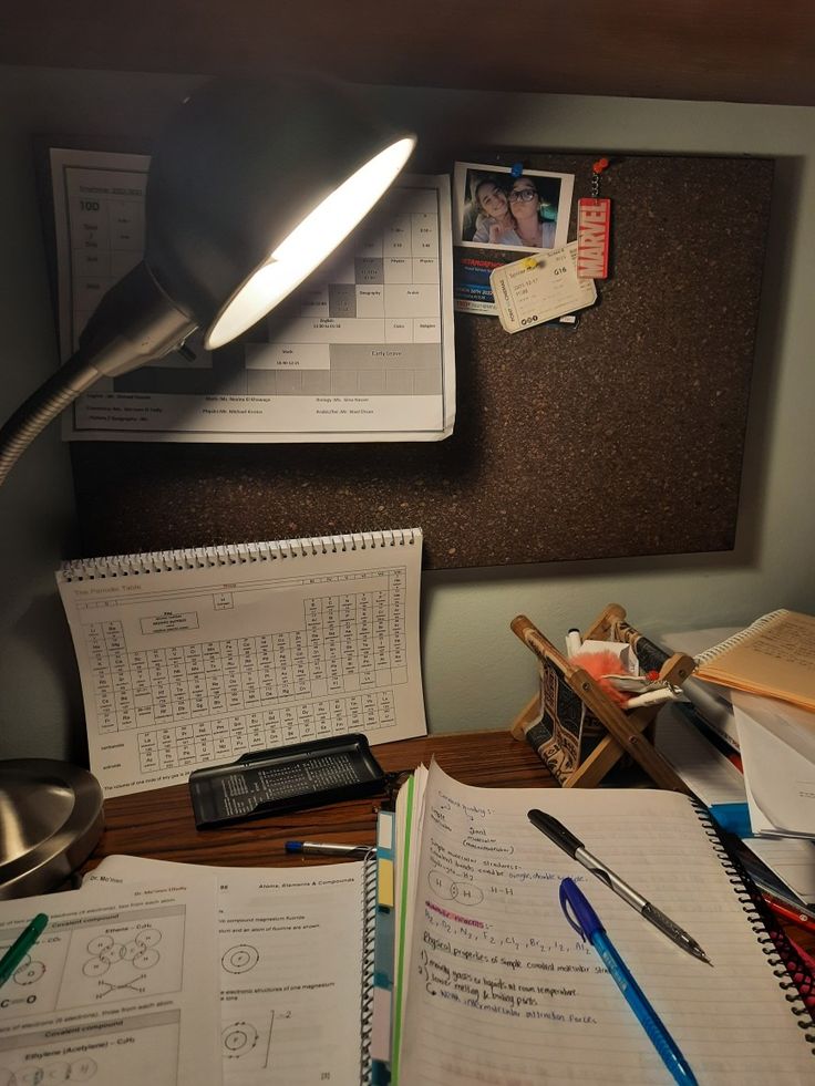 the desk is cluttered with papers, pens and a lamp on top of it