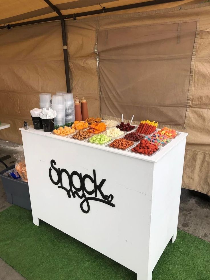 a white table topped with lots of different types of food next to a brown tent