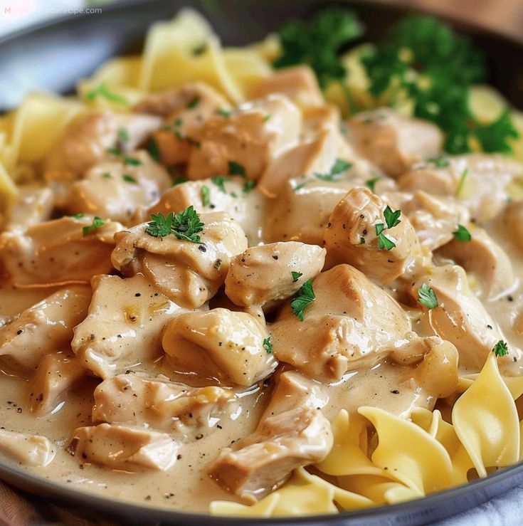 a plate of pasta with chicken and gravy on the top, garnished with parsley