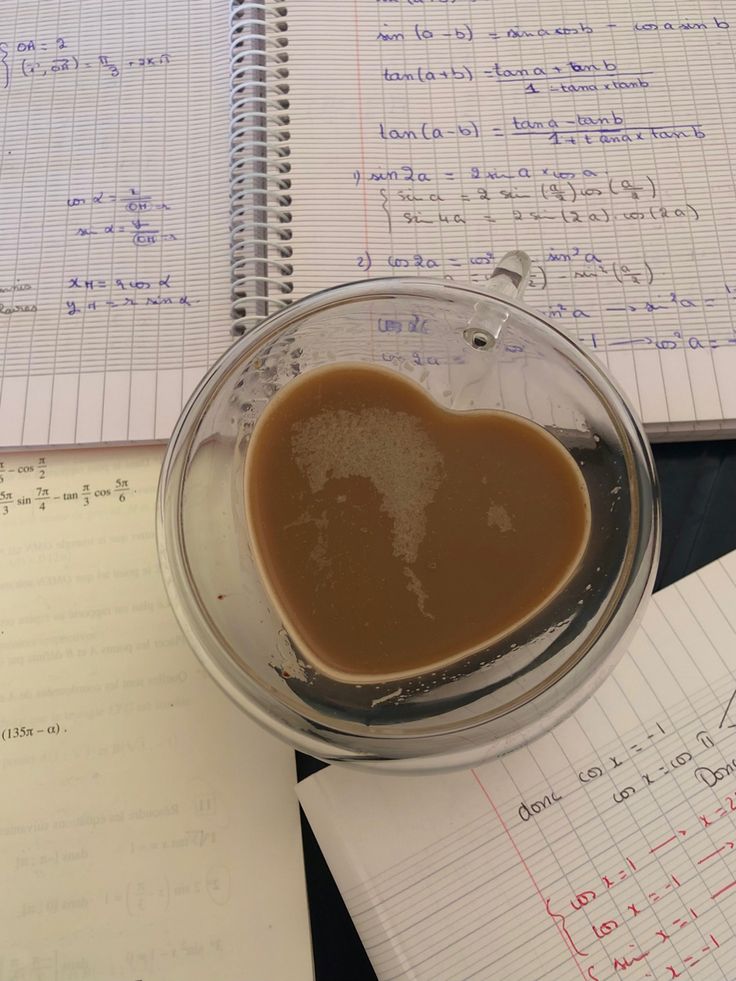 a heart - shaped substance is in a glass bowl on top of notebooks