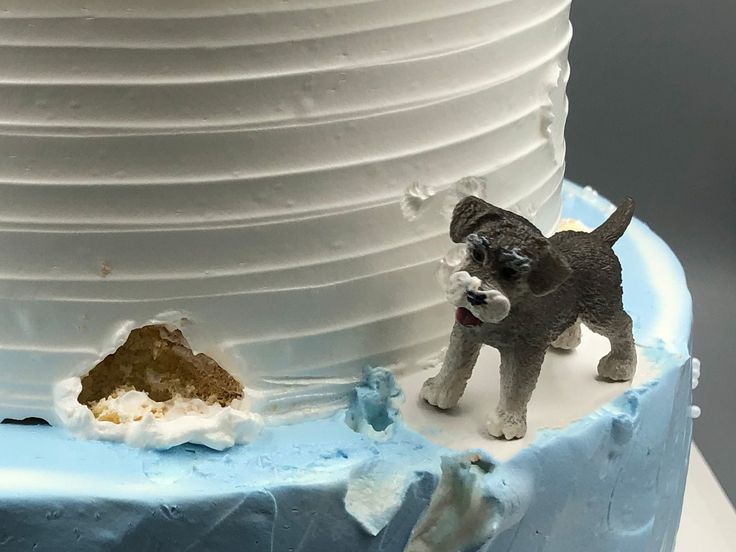 a small dog figurine on top of a frosted blue and white cake