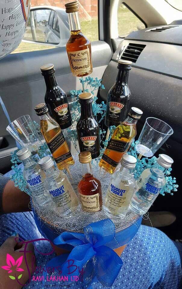 an arrangement of liquor bottles and glasses in the back seat of a car with a blue bow