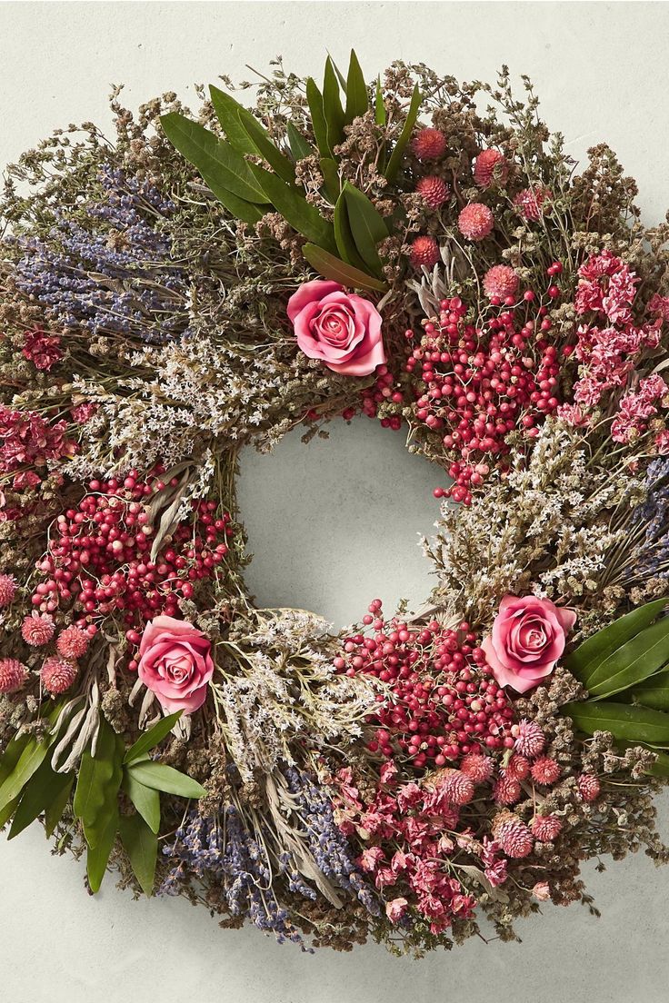 a wreath with pink flowers and greenery on it is displayed against a white background