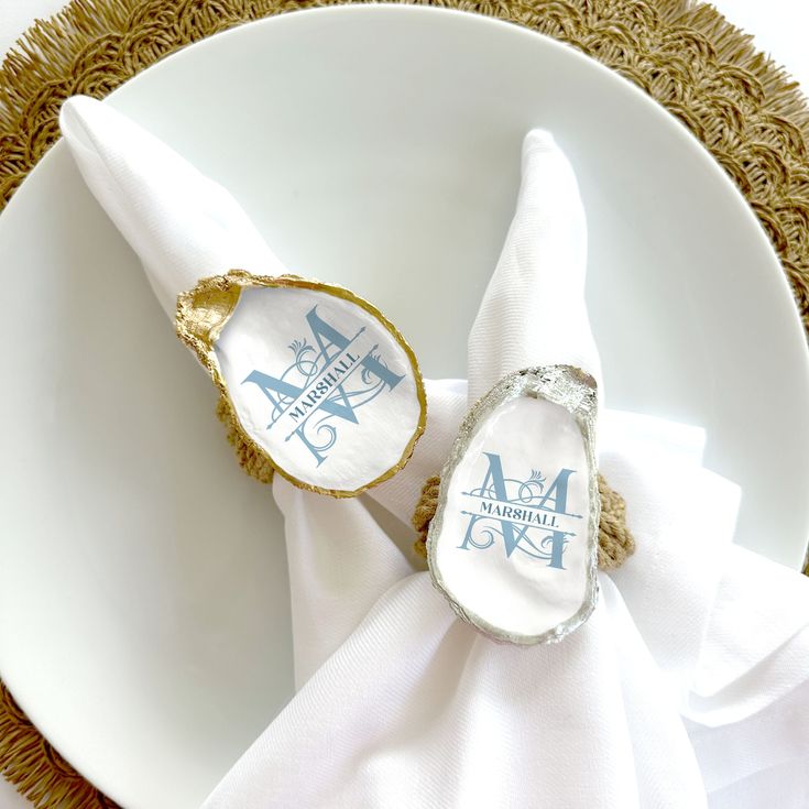 two napkins that are sitting on top of a white plate with gold trimming