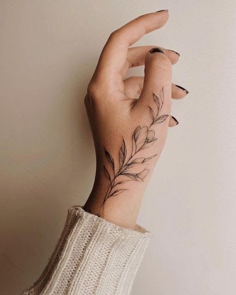 a woman's hand with a flower tattoo on her left wrist and the middle finger