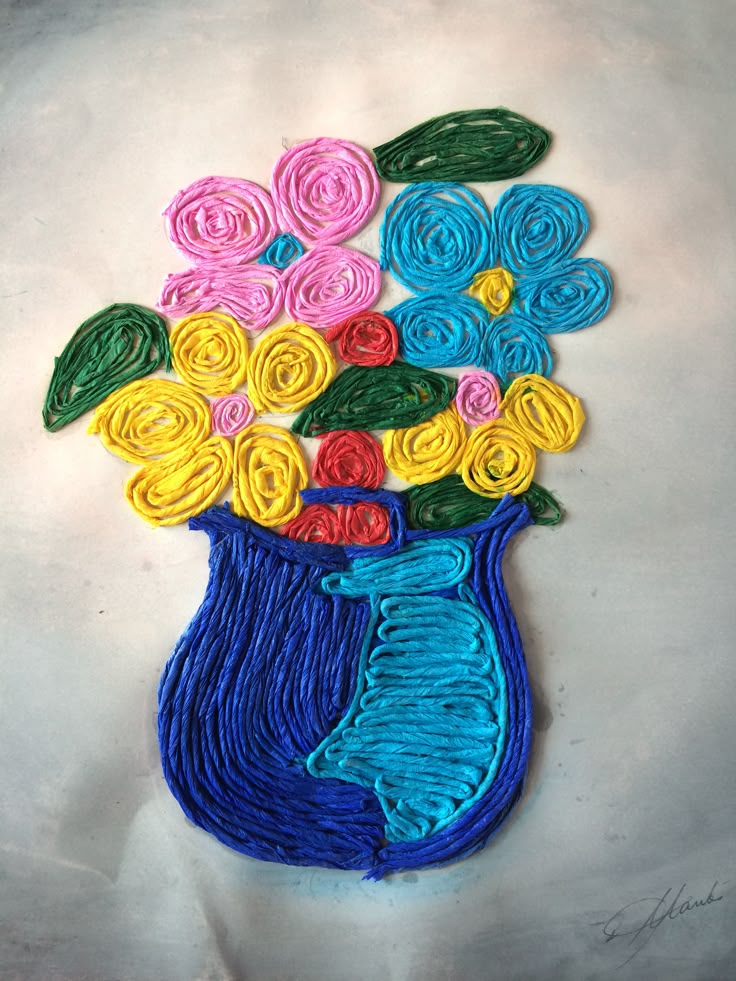 a blue vase filled with colorful flowers on top of a white table covered in crochet