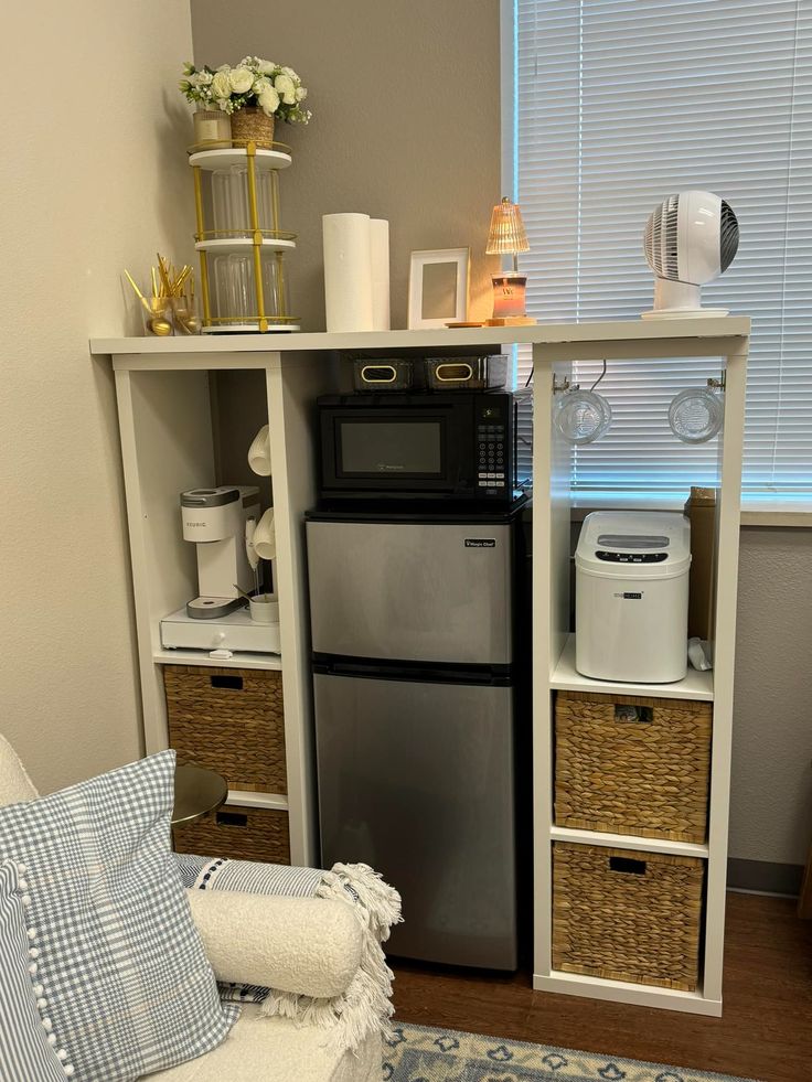 a small kitchen with a refrigerator, microwave and other items on the shelves in front of it