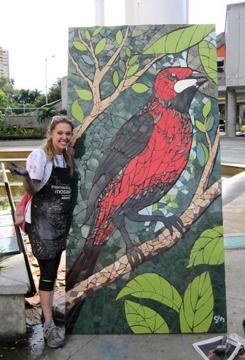 a woman standing next to a painting on the side of a building with a bird painted on it