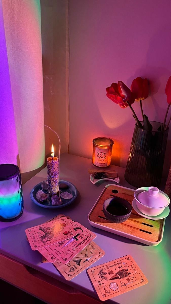 a table topped with candles and cards next to a vase filled with flowers on top of it