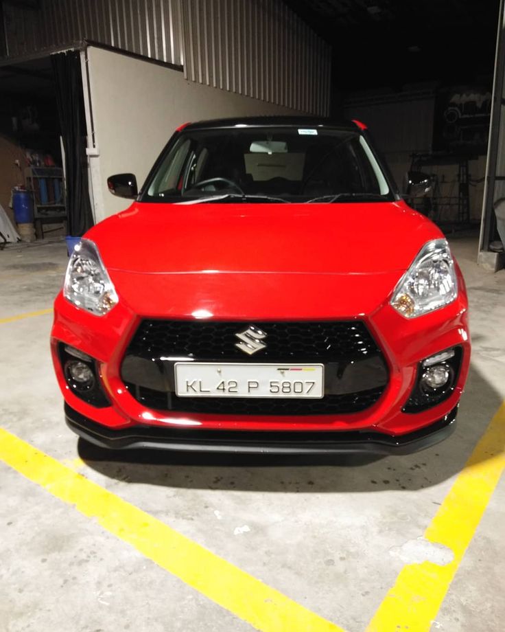 a red car is parked in a parking space with yellow lines on the floor and walls