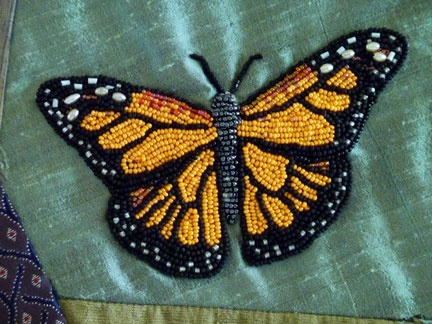 a close up of a butterfly on a piece of cloth with bead work around it