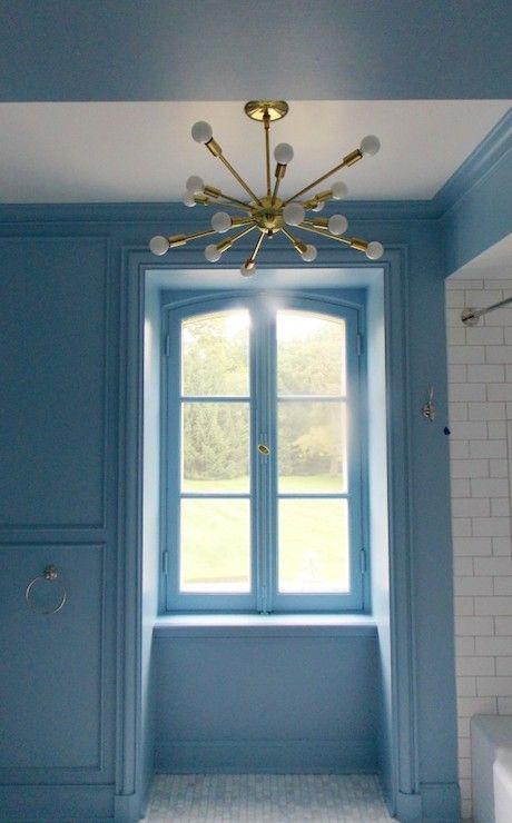 an empty bathroom with blue walls and white tile flooring, a chandelier hanging from the ceiling