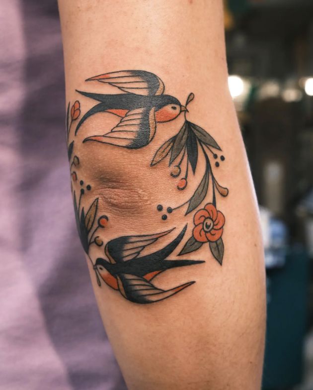 a woman's arm with a bird and flower tattoo design on the left forearm