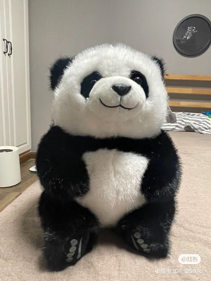 a large stuffed panda bear sitting on top of a bed