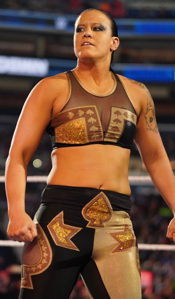 a female wrestler standing in the middle of a ring with her hands on her hips