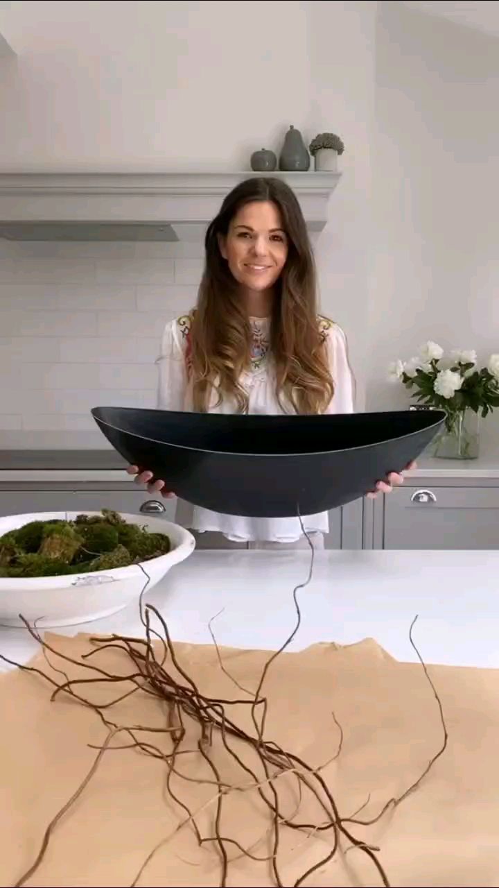 a woman standing in front of a counter holding up a bowl with food inside it