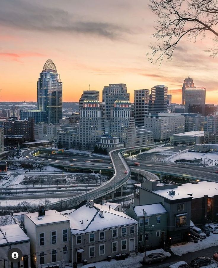 the city skyline is covered in snow as the sun sets over the buildings and roads