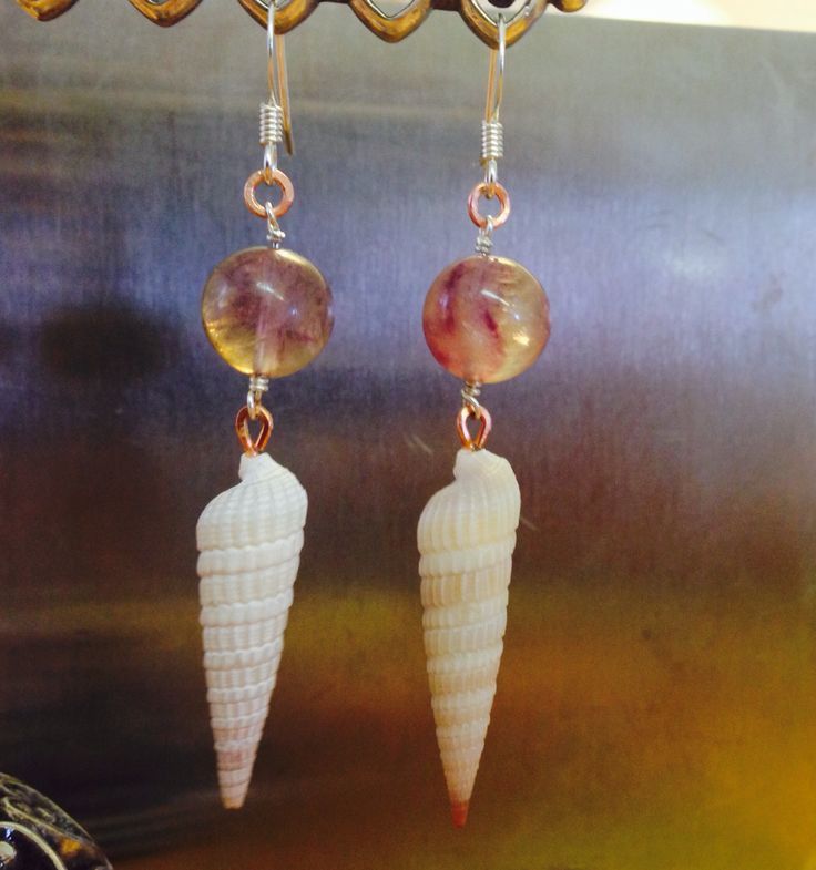 two seashells hanging from hooks on a piece of metal with bead and glass beads