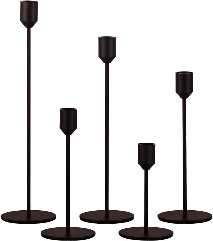 three black candlesticks are standing in front of each other