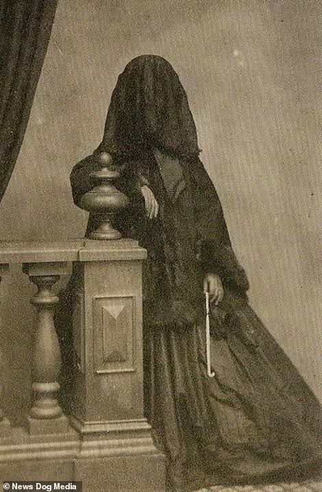 an old black and white photo of a woman standing next to a table with a clock on it