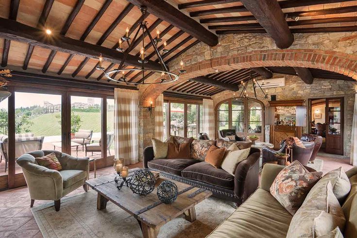 a living room filled with lots of furniture next to a stone wall covered in windows