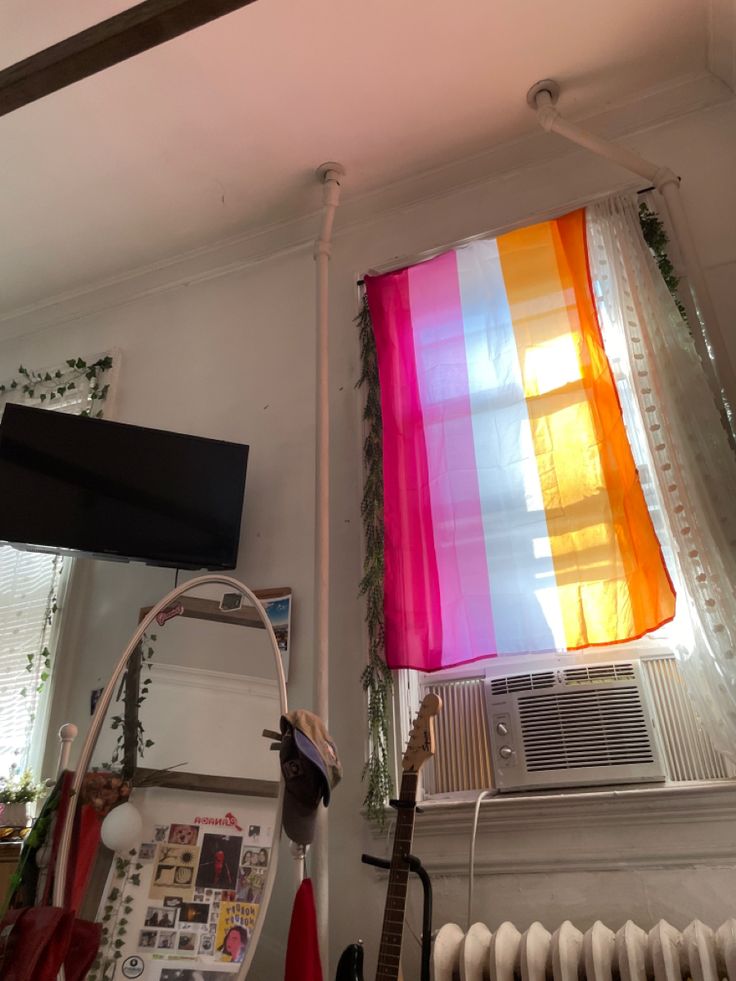 an electric heater sitting next to a window with a colorful curtain hanging from it's side