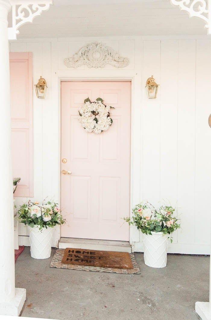 a pink front door with two white flower pots