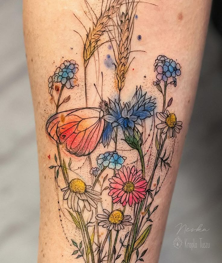 a colorful tattoo with flowers and a butterfly on it's thigh, in the middle of a photo