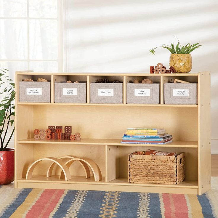 a wooden shelf with bins and baskets on it in front of a potted plant