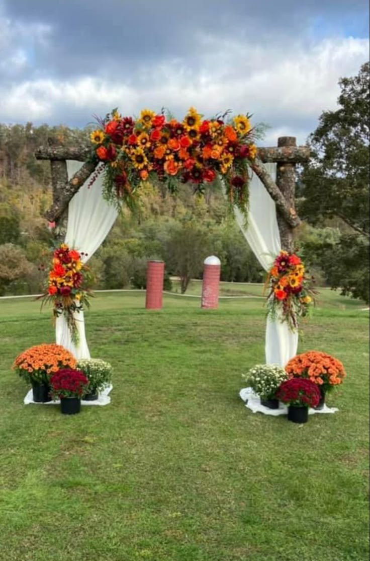 an outdoor wedding set up with orange and red flowers