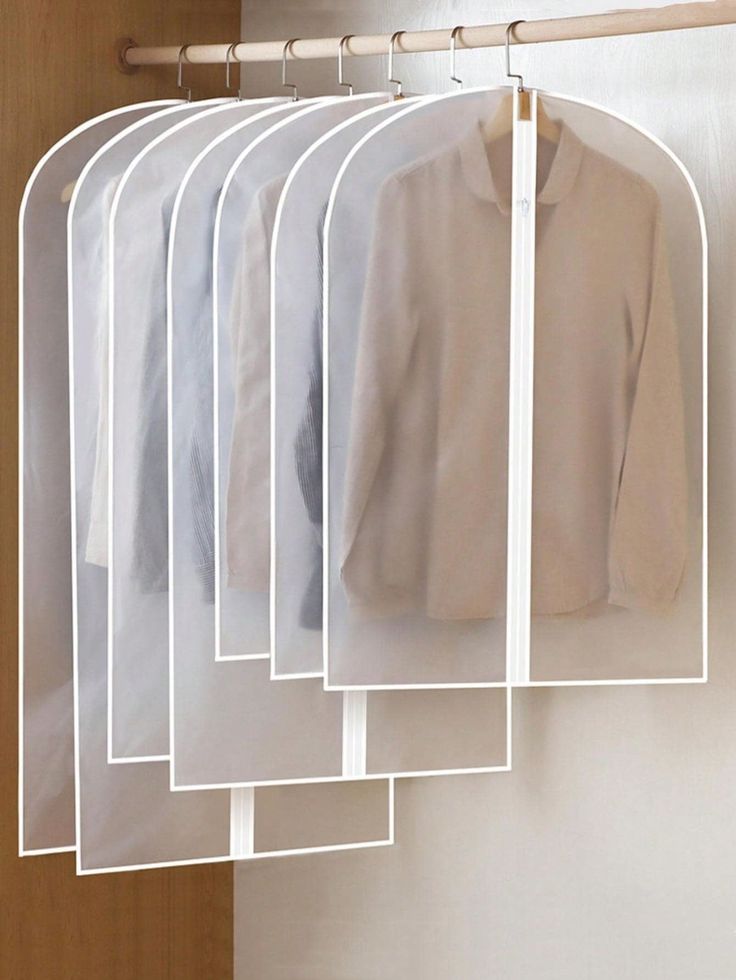 five shirts hanging on a rack in front of a door with clothes hanging from it