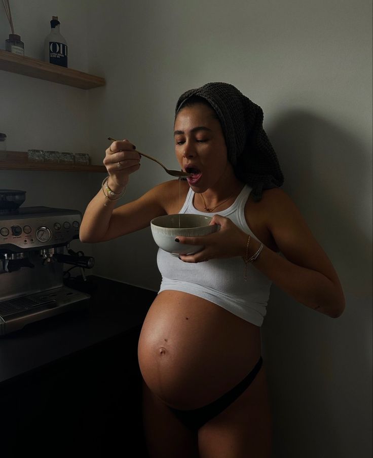 a pregnant woman eating food from a bowl