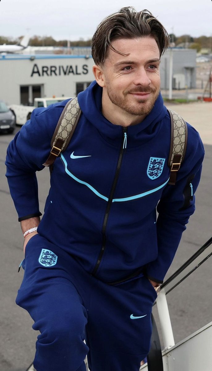 a man in blue tracksuits standing next to a car